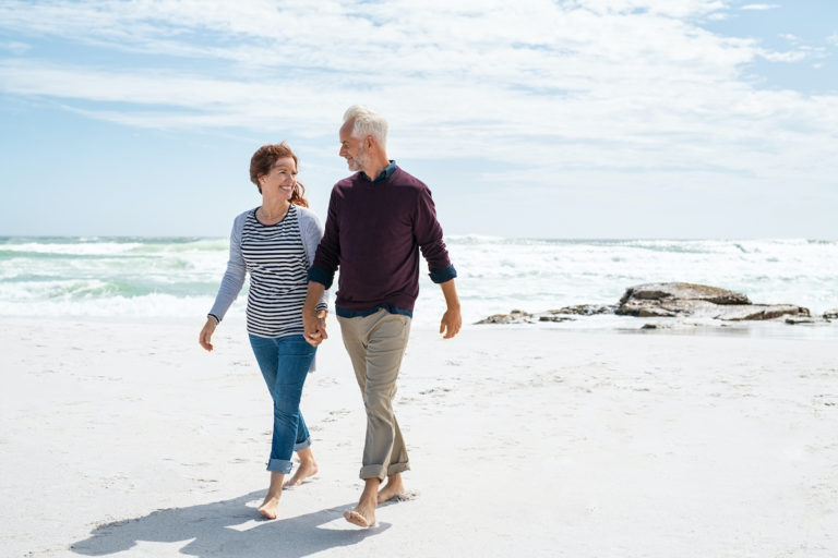 happy couple walks down beach after bioidentical hormone replacement therapy