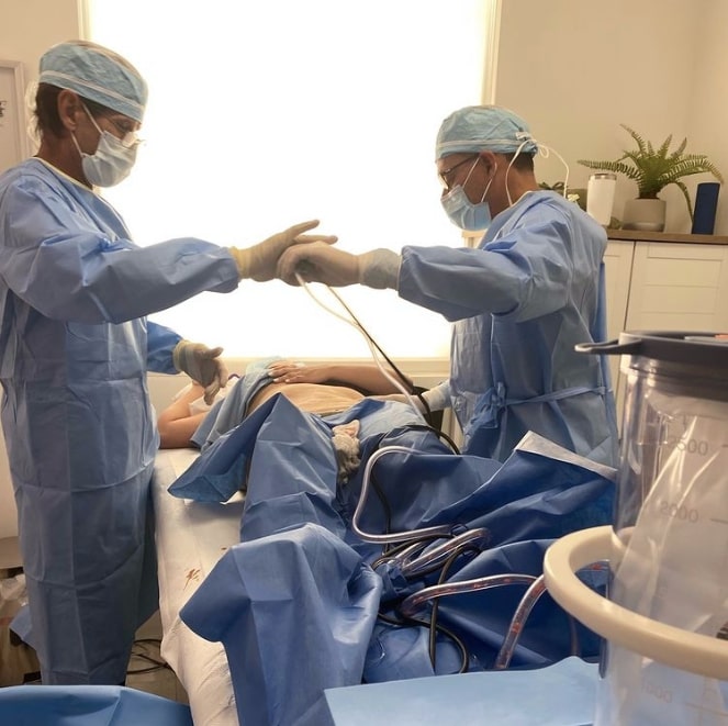 two doctors performing liposuction patient table
